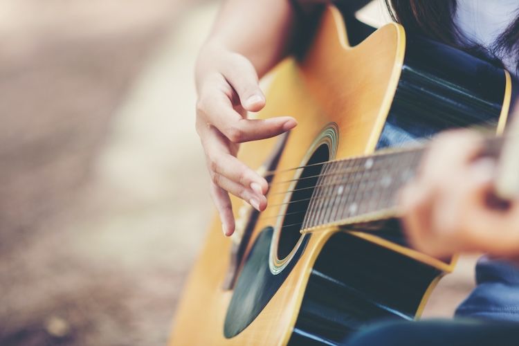 Guitarrista tocando su guitarra con las uñas y las yemas de sus dedos